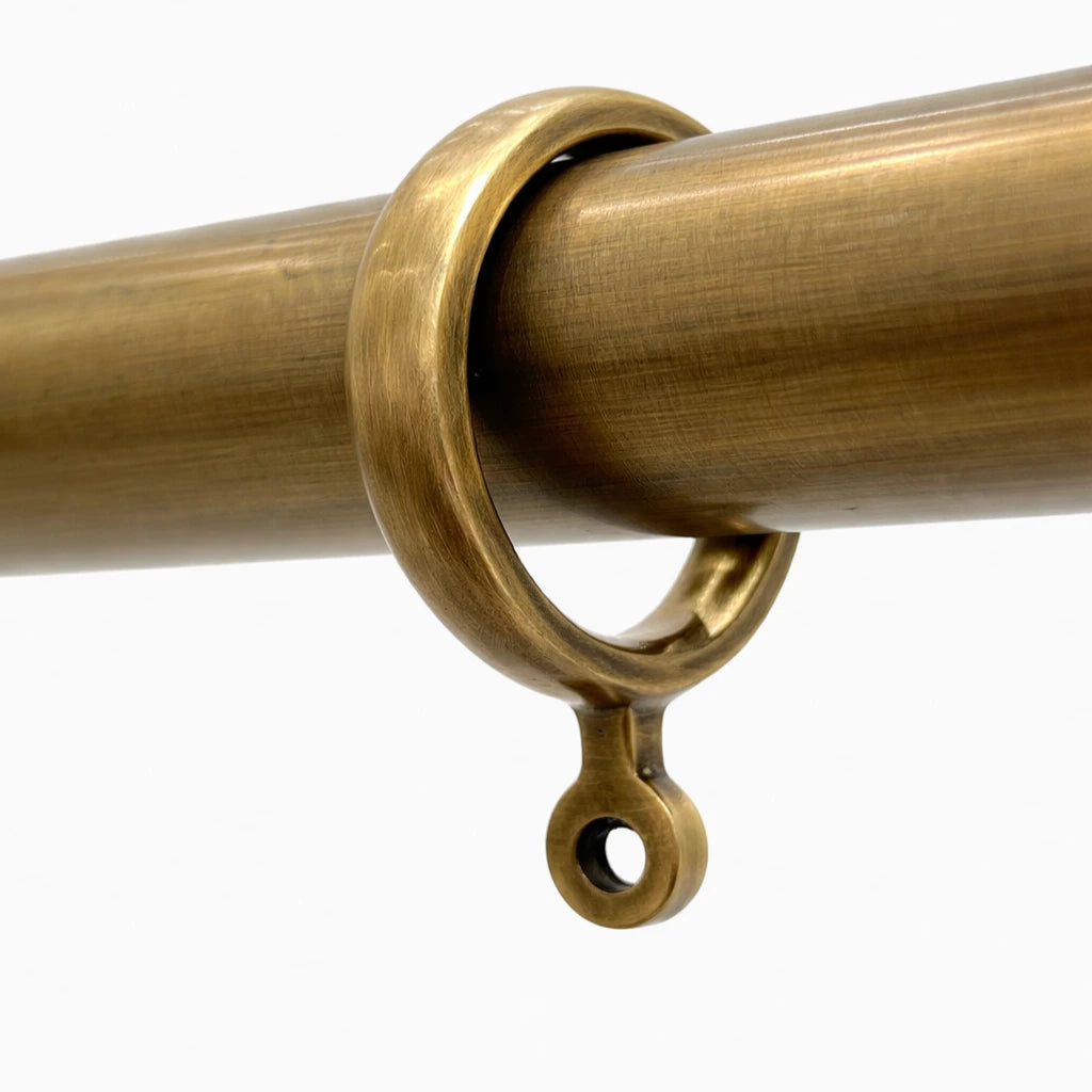 Gold curtain rod with decorative ring on a white background