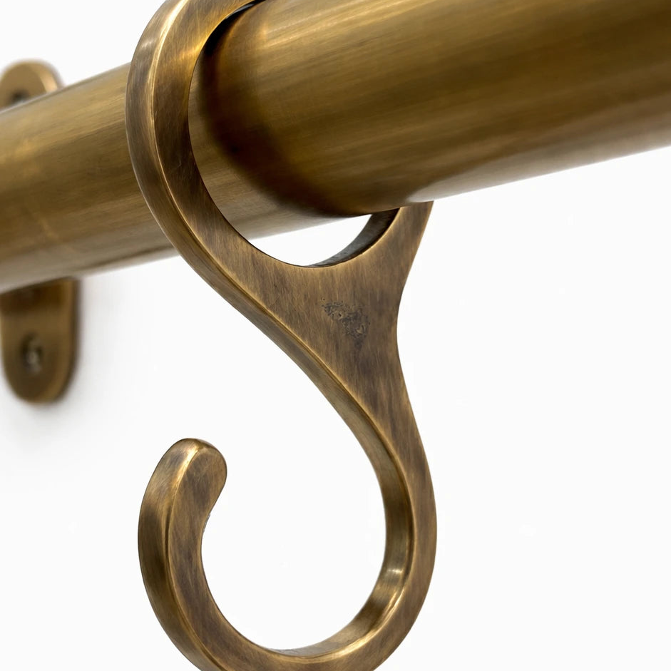 Brass curtain rod with decorative bracket on a white background