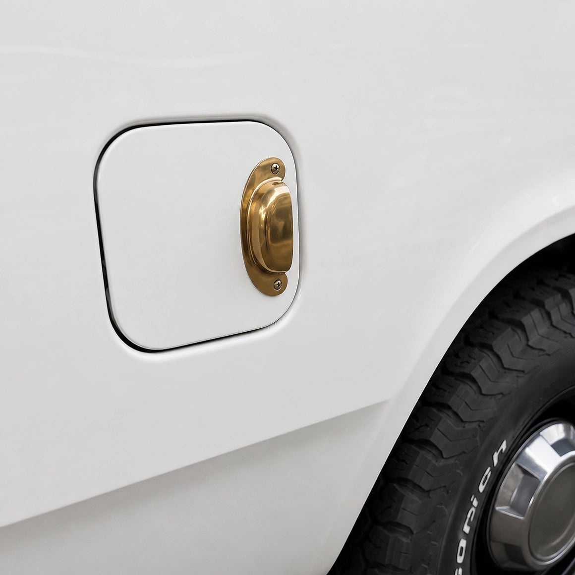 Close-up of a white car's fuel cap with a gold finish.