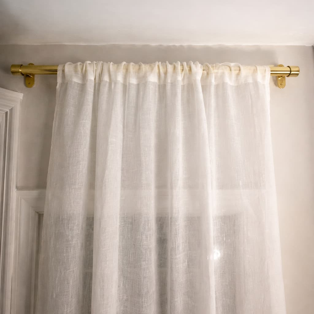 White curtain with gold rod on a white wall