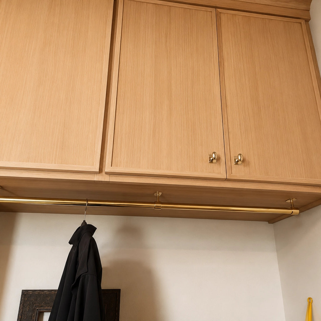 Wooden kitchen cabinets with a gold handle and a black jacket hanging below.