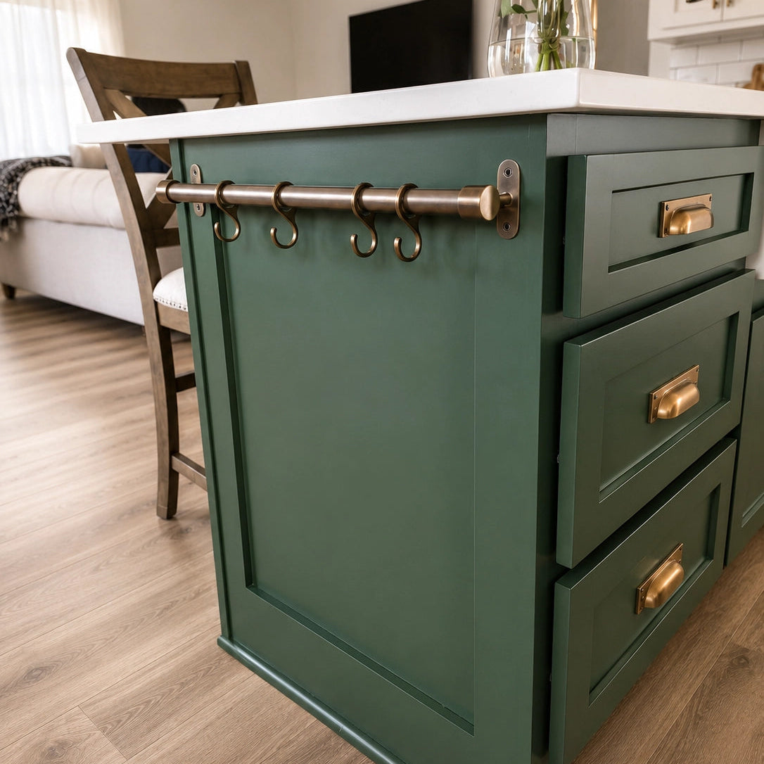 Green kitchen island with white countertop and gold fixtures in a home setting.