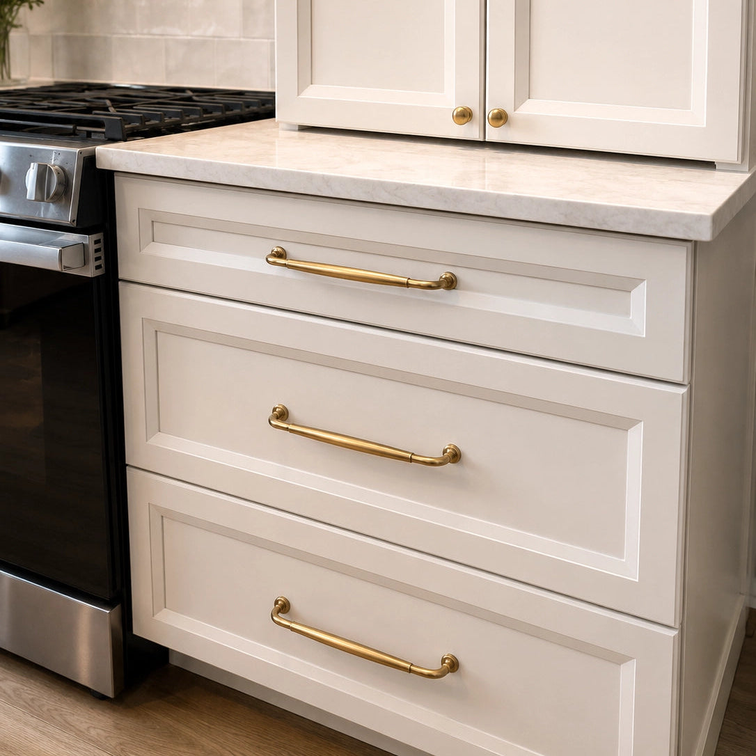 Kitchen with white cabinets, gold handles, and a tiled backsplash.