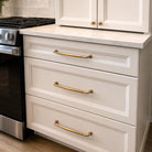 Kitchen with white cabinets, gold handles, and a tiled backsplash.