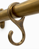 Brass curtain rod with decorative bracket on a white background