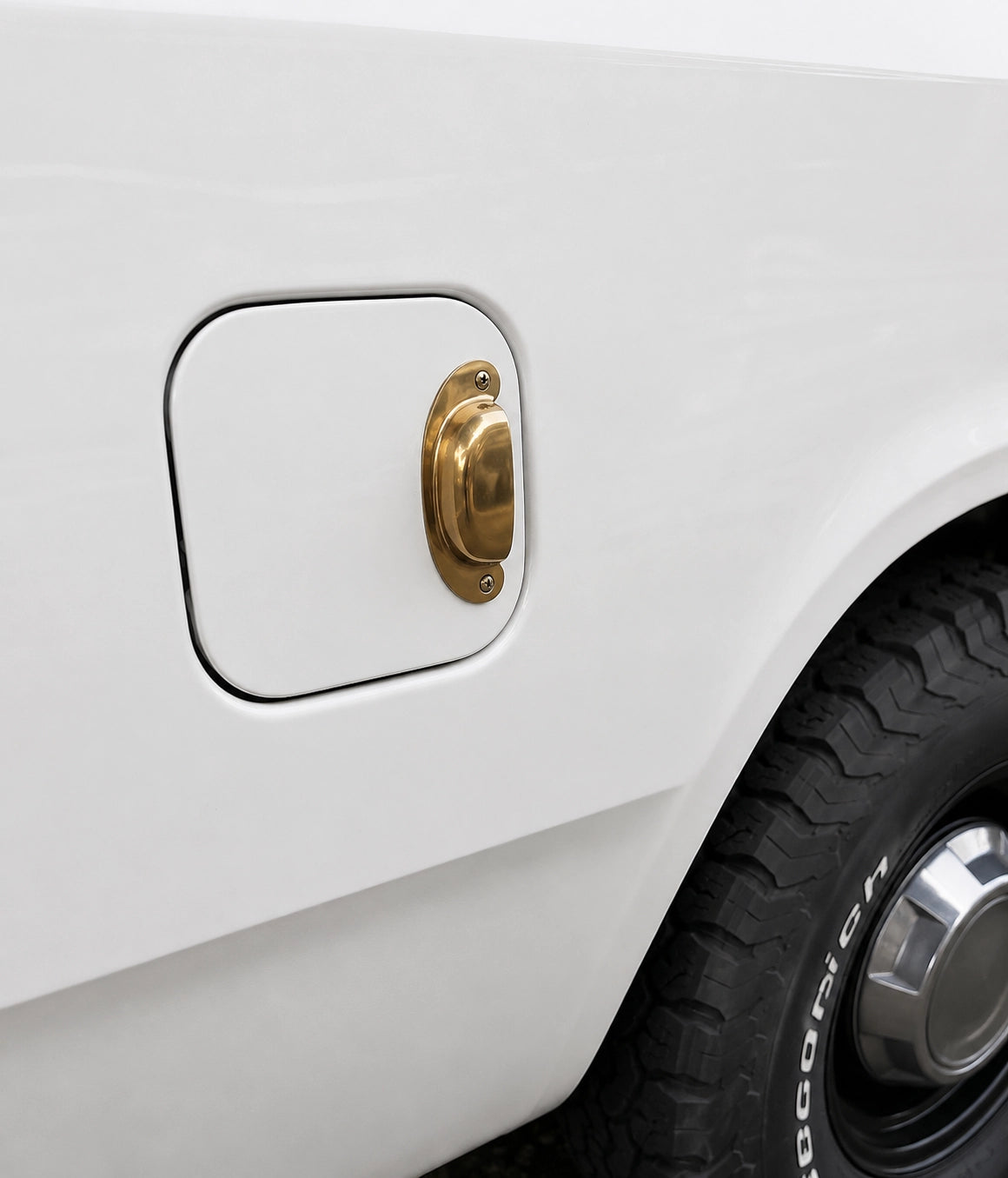 Close-up of a white car's fuel cap with a gold finish.
