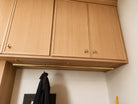 Wooden kitchen cabinets with a gold handle and a black jacket hanging below.